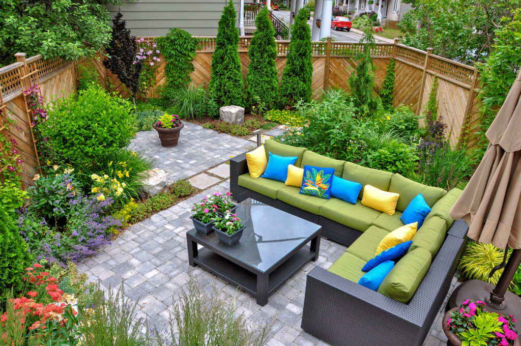 outdoor patio space with lots of shrubs and a large fence